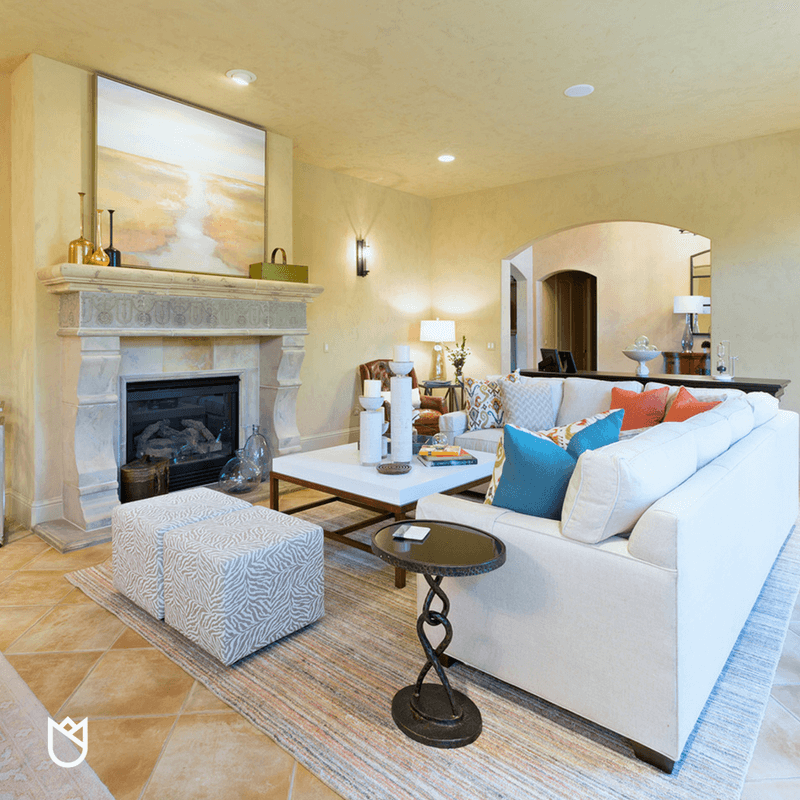 A white sectional atop a large wool rug anchors this room and give the off centered fireplace new meaning