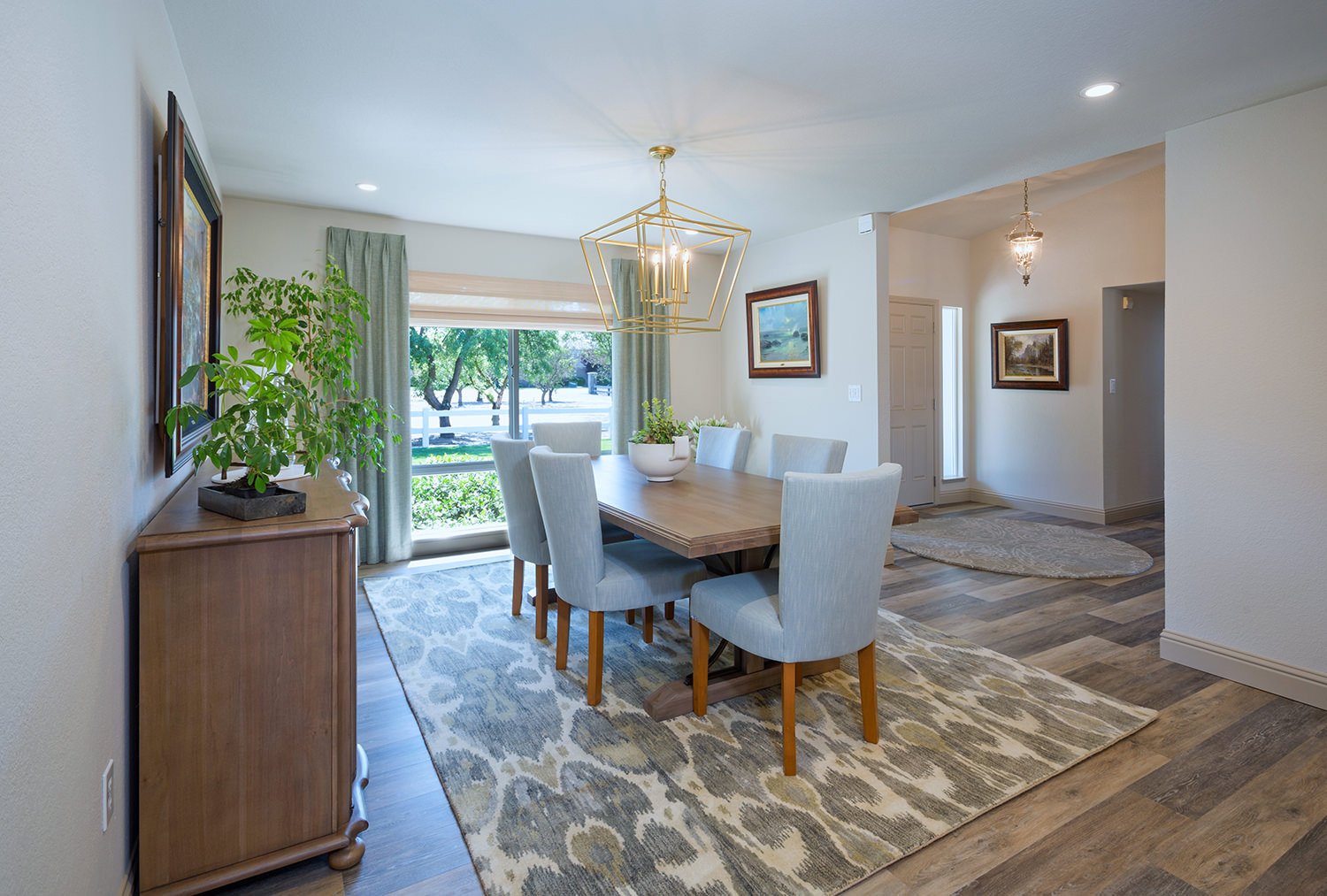 dining room table upholstered chairs area rug gold chandelier wood sideboard sage green drapery ekat patterned wool area rug