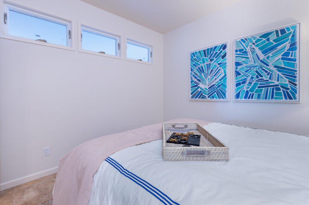 Santa Cruz Condo Bedroom Conversion With Transom Windows, Coastal Artwork, And Layered Neutral Bedding